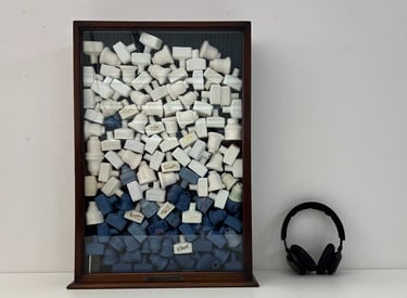 A vintage glazed cabinet holds a stack of 100 small ceramic bottles in blue and white porcelain.
