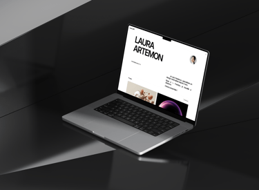A laptop on a desk displaying the Laura.art website