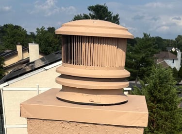 A newly waterproofed and resurfaced chimney with a modern round chimney cap, installed by Roslyn Chimney in Roslyn, New York