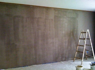 Taupe-coloured wall prepared for decoration with hand-painted art, a dropcloth and ladder