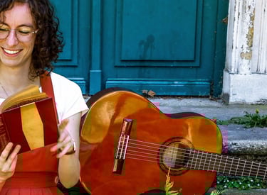 musicienne en train de lire un livre/a woman in a red dress reading on stairs with guitar beside her