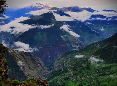Mountain ridges with clouds and distant snowy peaks.