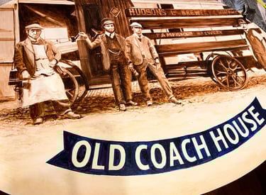 Close-up of angled pub sign with painted brewery staff