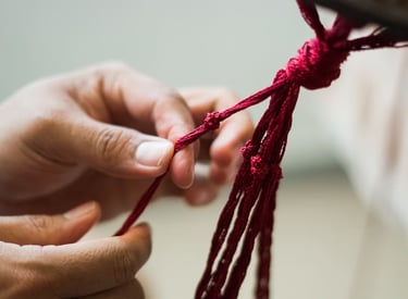 Atado a mano de un nudo de borla roja para tejido textil tradicional y artesanía decorativa..