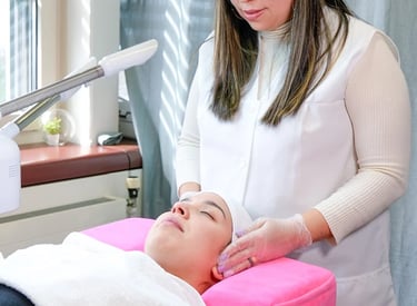 Professional esthetician performing a facial treatment and massage for a client at a skincare spa.