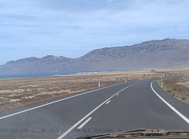 a car driving down a road with mountains in the background