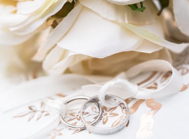 a bouquet of white roses and wedding rings