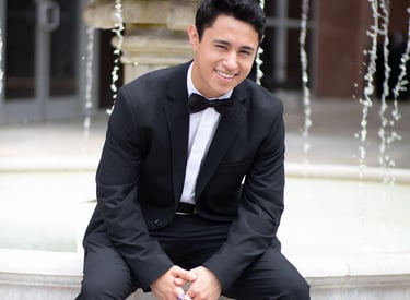 Sonny Velasco in a suit sitting on a fountain