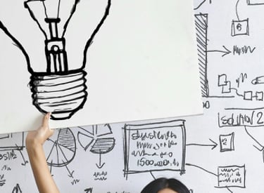 a woman holding up a sign with a picture of a light bulb bulb
