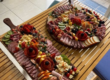 Two large charcuterie and cheese boards beautifully displayed on wooden trays.