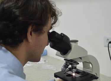 Citologista clínico analisando amostra em microscópio.