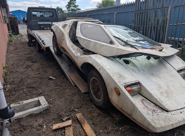 custom build car stuck in mud being winched onto a recovery truck