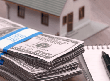 a stack of money bills and a pen and pen on a desk