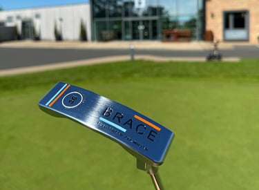 Brace forged golf putter in front of golf clubhouse far