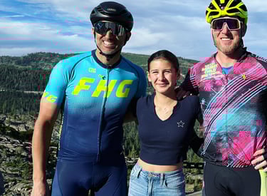 Two men cyclists posing with a girl in the outdoors