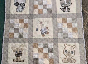 Patchwork quilt with plaid squares and embroidered woodland animals in a playful 4x5 grid.