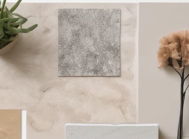 A modern interior space with a focus on minimalism. There is a large, abstract sculpture resembling a person or character with spherical forms, positioned on a surface with open books scattered alongside. The sunlight casts shadows across the room, highlighting the neutral tones and sleek, contemporary design. A decorative grid structure adds an element of intrigue on the left side. The materials used include marble and wood, contributing to the sophisticated atmosphere.