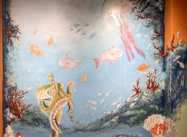 An active, life filled colorful coral reef of fish, octopus, and jelly fish wall mural by Kathy LaFollett.