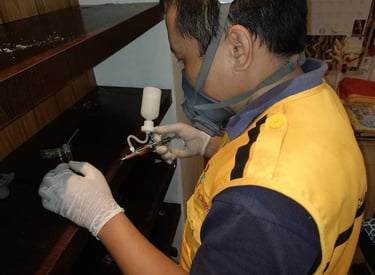 Professional pest control technician wearing a respirator mask and spraying pesticide in a wooden cabinet.