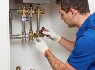 Plumber fitting heating pipes in a commercial building.