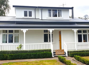 White weatherboard home with dark roof and porch detailing, freshly painted by Gee Cee Painters