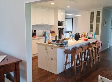 White kitchen with central island and wood floors, freshly painted by Gee Cee Painter