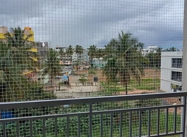 A technician carefully installing a strong monkey safety net on a residential balcony in Bengaluru.