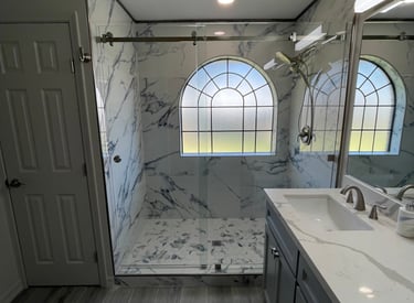 Modern master bathroom featuring a marble walk-in shower with glass doors and a double vanity.
