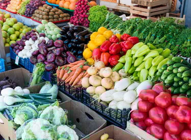 Fresh organic vegetables displayed at a farmers market, including leafy greens, carrots, and seasonal produce.