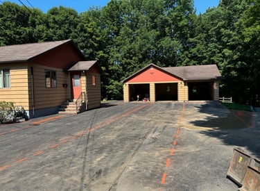 Residential asphalt driveway with orange marking lines leading to a three-car detached garage.