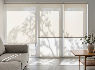 Modern living room featuring cream-colored window roller shades with soft tree shadows.