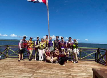 A group of friends wearing life jackets standing on a wooden boat deck for a tropical water tour.