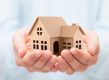 a person holding a paper house model of a house