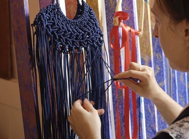 Mujer bordando una artesanía con hilo de color azul, ussndo diferentes técnicas