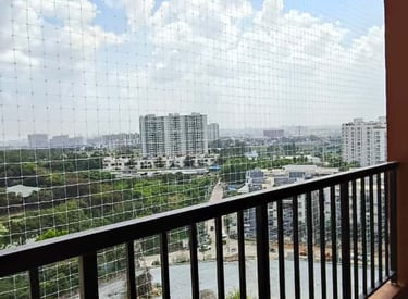 Close-up of a sturdy safety net securing a balcony with a view of Coimbatore skyline.