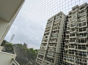 Technician carefully fitting a safety net on a balcony railing.