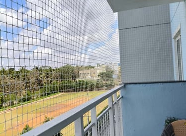 Close-up of a sturdy pigeon net securely fitted on a balcony railing in SHSR Layout.