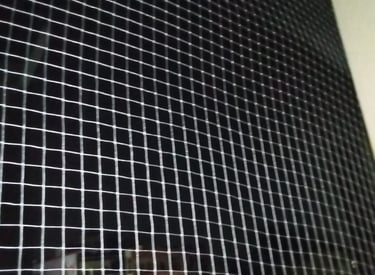 A wide-angle shot of a commercial building facade covered with pigeon nets to prevent bird intrusion