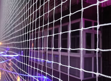 Installation team fitting pigeon nets on a rooftop terrace under bright Chennai sunlight.