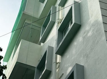Wide shot of a residential building in Chennai with newly installed pigeon nets on balconies.