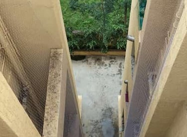 Safety net covering an apartment duct area with clear sky in background.