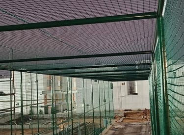 A rooftop cricket net installation with a clear blue sky in Whitefield.