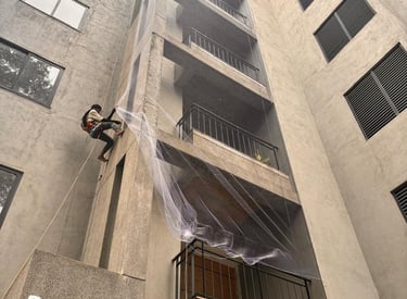 Technician carefully installing pigeon nets on an apartment duct area with precision.
