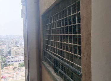 Wide shot of a multi-story building in Kannamangala with pigeon nets covering all open windows.