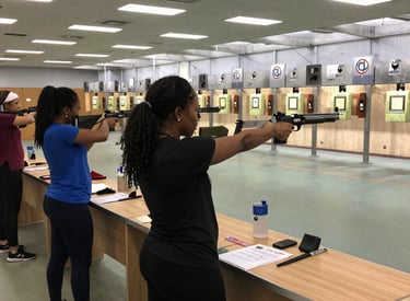 A group of women practicing shooting drills with focused attention and smiles.