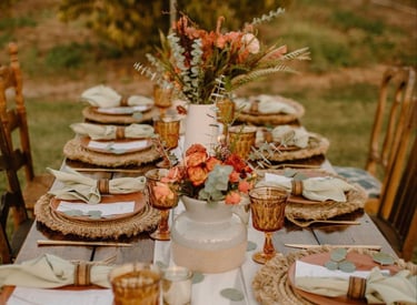 Mesa rústica de boda con platos apilados y centro floral otoñal.