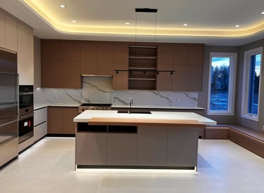 Modern minimalist kitchen featuring a marble island, custom brown cabinetry, and elegant cove ceiling lighting.