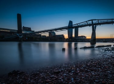 London's Millennium Bridge and Tate Modern silhouette over River Thames during a blue hour sunset.