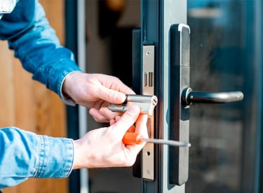 a person is holding a cell phone and looking at the door handle of a door
