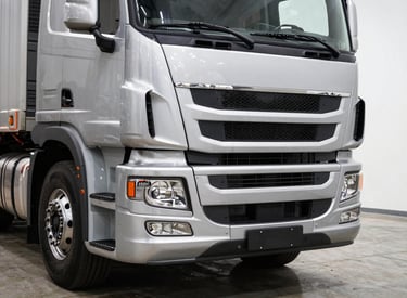 Close-up front view of a heavy-duty Chinese long-haul truck cab in a bright showroom, chrome grille and headlights in sharp detail, white studio lighting, scale visible against concrete floor